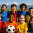 Young soccer players in team uniforms standing together on a field with mountains in the background