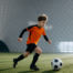Soccer player dribbling ball inside a large indoor dome facility with curved ceiling
