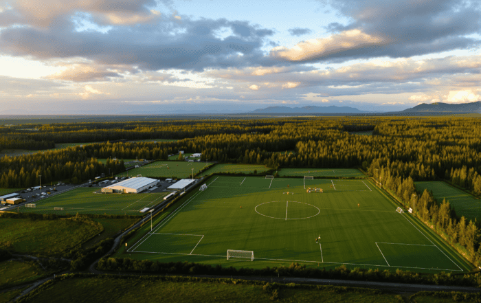 Aerial view of a multi-field soccer complex in Alaska surrounded by forest