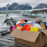 Soccer equipment in a shipping box on an Alaskan dock next to a small seaplane