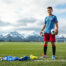 Youth soccer player in uniform on an Alaskan field with mountain backdrop